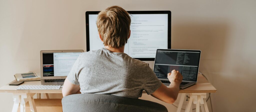 Teen programming with multiple laptops in a modern workspace. Ideal for tech and education themes.