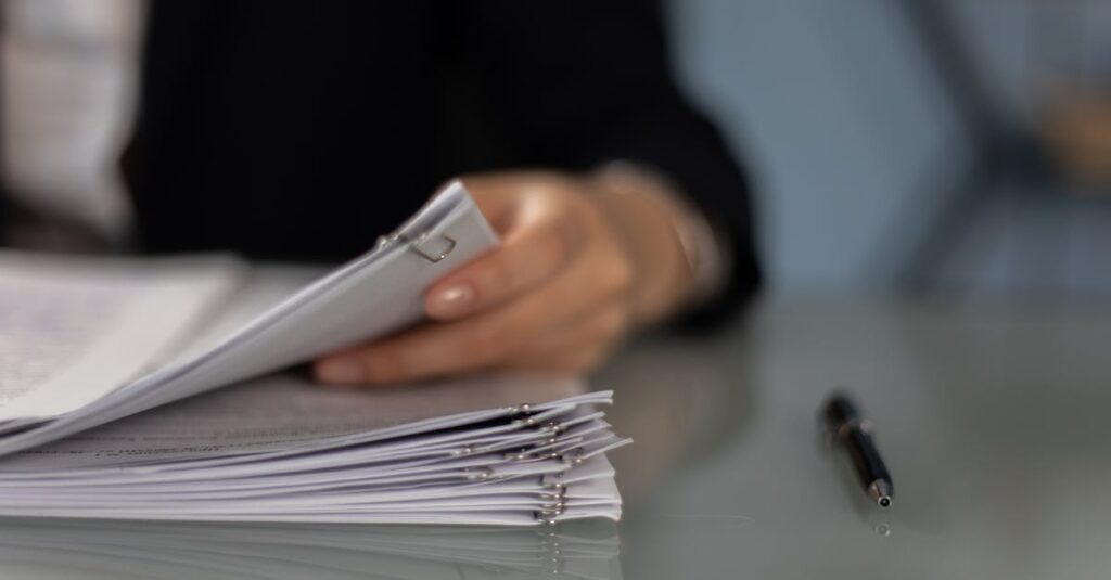 Close-up of a professional organizing a stack of documents on a desk.